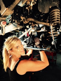 a woman working on a vehicle under a car